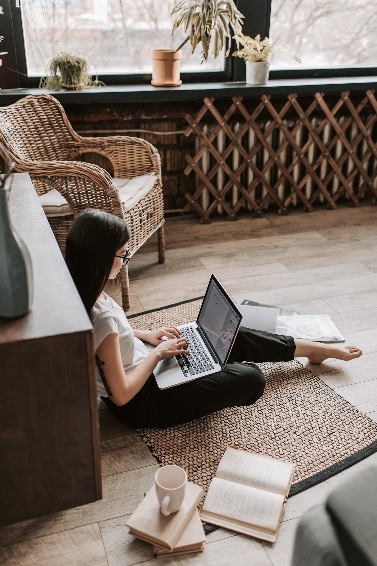 Young woman working on a laptop in a cozy room with plants and books